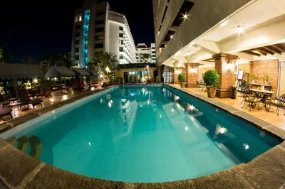 a large swimming pool in a hotel at night at Copacabana Apartment Hotel in Manila