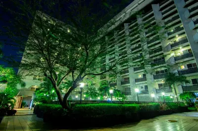 a building with a tree in front of it at night at Copacabana Apartment Hotel in Manila