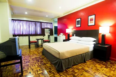 a hotel room with a bed and a flat screen tv at Copacabana Apartment Hotel in Manila