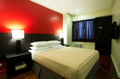 a bedroom with a large bed with a red wall at Copacabana Apartment Hotel in Manila