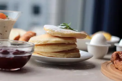 a stack of pancakes on a plate with a bowl of jam at Discovery Suites Manila, Philippines in Manila