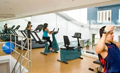 a man exercising in a gym with people on treadmills at St Giles Hotel Makati in Manila