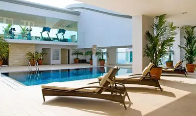 a swimming pool with two lounge chairs in a building at St Giles Hotel Makati in Manila