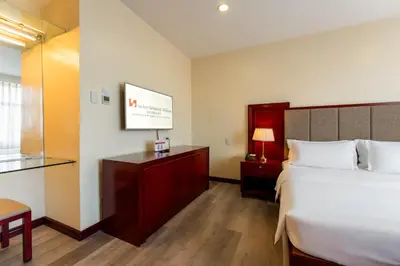 a hotel room with a bed and a tv at Swiss-Belhotel Blulane in Manila