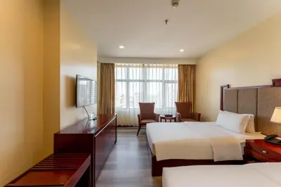 a hotel room with two beds and a desk at Swiss-Belhotel Blulane in Manila
