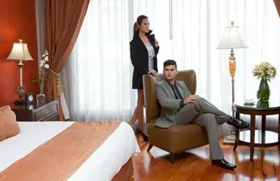 a woman standing behind a man sitting in a chair in a hotel room at Hotel Celeste Makati in Manila