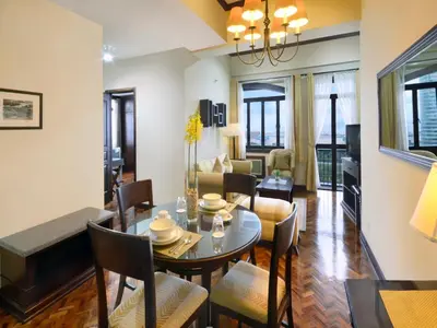 a dining room and living room with a table and chairs at Parque España Residence Hotel in Manila