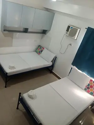 a small room with two beds and a air conditioner at Alicia Apartment in Manila