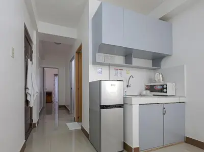 a white kitchen with a refrigerator and a microwave at Alicia Apartment in Manila