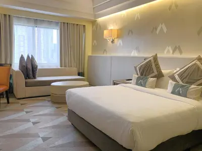 a hotel room with a large bed and a couch at Hotel Benilde Maison De La Salle in Manila