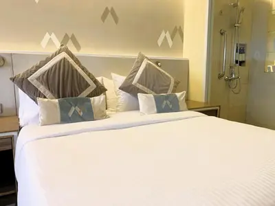 a bedroom with a large white bed with pillows at Hotel Benilde Maison De La Salle in Manila