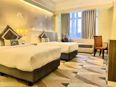 a hotel room with two beds and a desk at Hotel Benilde Maison De La Salle in Manila