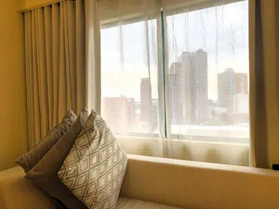a couch with a pillow in front of a window at Hotel Benilde Maison De La Salle in Manila