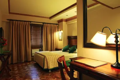a hotel room with a bed and a desk and a mirror at Herald Suites in Manila