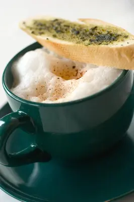 a black cup of coffee with a piece of bread in it at Herald Suites Solana in Manila