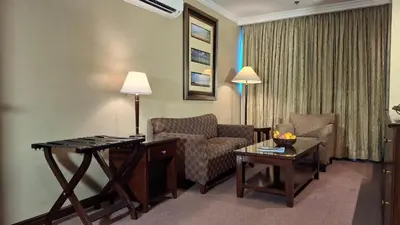 a hotel room with a couch and a chair and a table at Herald Suites Solana in Manila