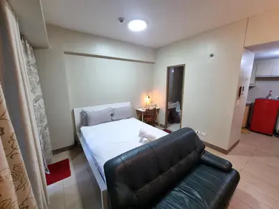 a bedroom with a bed and a leather couch at Palm Tree Condos near MNL Airport Terminal 3 by ELR in Manila