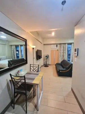 a living room with a table and a couch at Palm Tree Condos near MNL Airport Terminal 3 by ELR in Manila