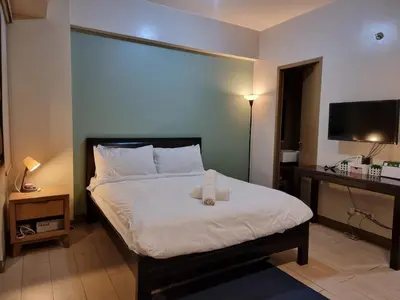 a bedroom with a bed and a desk and a television at Palm Tree Condos near MNL Airport Terminal 3 by ELR in Manila