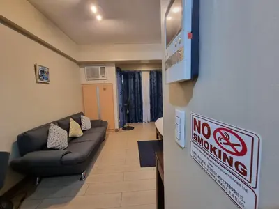 a living room with a no smoking sign on a wall at Palm Tree Condos near MNL Airport Terminal 3 by ELR in Manila
