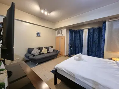 a living room with a bed and a couch at Palm Tree Condos near MNL Airport Terminal 3 by ELR in Manila