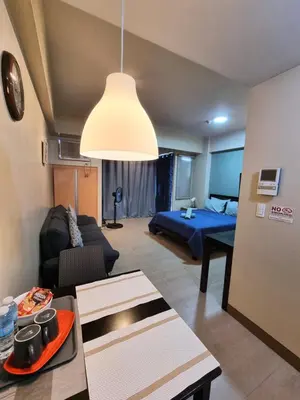 a living room with a couch and a bed at Palm Tree Condos near MNL Airport Terminal 3 by ELR in Manila
