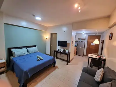 a bedroom with a blue bed and a couch at Palm Tree Condos near MNL Airport Terminal 3 by ELR in Manila