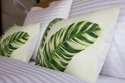 three pillows with green leaves on a bed at KL Executive Greenbelt (KLX) in Manila