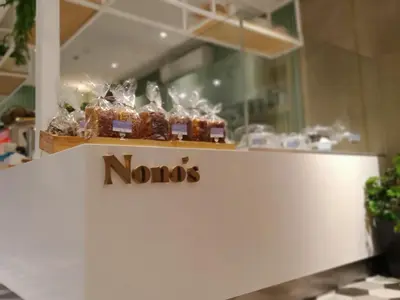 a noos sign on top of a counter with desserts at KL Executive Greenbelt (KLX) in Manila