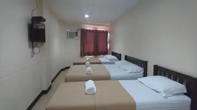 three beds in a hotel room with towels on them at Calamba Pension Plaza in Calamba