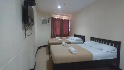 two beds in a small room with a television at Calamba Pension Plaza in Calamba