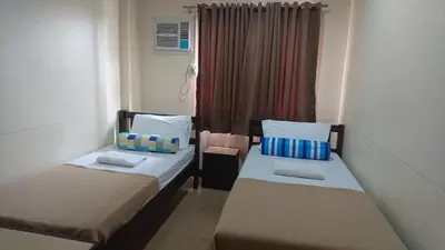 a small room with two beds and a window at Calamba Pension Plaza in Calamba