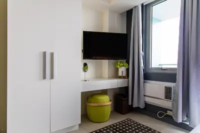 a room with a desk and a tv and a window at Azure Urban Beach Resort Manila by Radlett in Manila