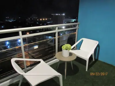 a balcony with a white chair and a table and a window at Azure Urban Beach Resort Manila by Radlett in Manila