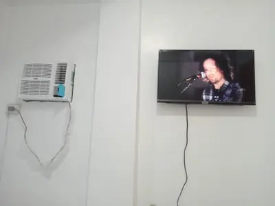 a flat screen tv hanging on a wall with a microphone at MJ Home in Manila