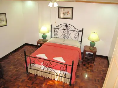 a bedroom with a bed with a red blanket and two lamps at Makati Suites at Travelers Inn in Manila