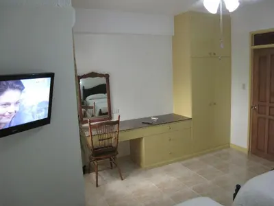 a bedroom with a desk with a mirror and a tv at Makati Suites at Travelers Inn in Manila