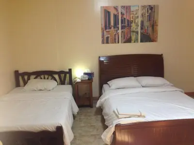 a bedroom with two beds and a picture on the wall at Makati Suites at Travelers Inn in Manila