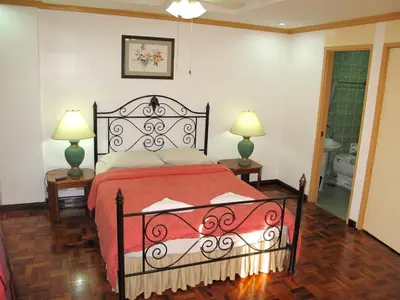 a bedroom with a bed with a red blanket and two lamps at Makati Suites at Travelers Inn in Manila