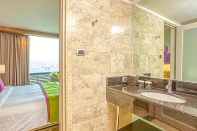 a bathroom with a sink and a bed in a room at Eastwood Richmonde Hotel Quezon City in Manila