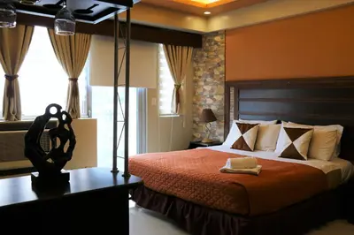 a bedroom with a bed with a red comforter at One Palm Tree Villas MANILA in Manila