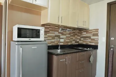 a kitchen with a microwave on top of a refrigerator at One Palm Tree Villas MANILA in Manila