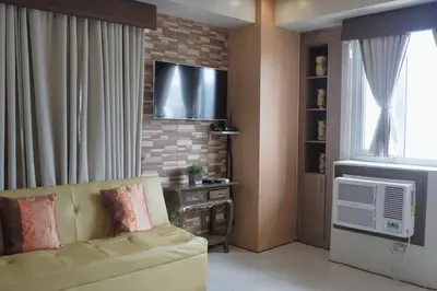 a living room with a couch and a flat screen tv at One Palm Tree Villas MANILA in Manila