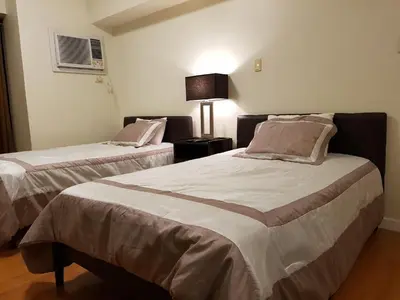 a bedroom with two beds and a lamp at Eton Baypark in Manila