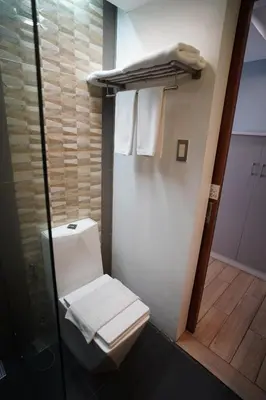 a bathroom with a toilet and a shower with towels at Heroes Hotel in Manila