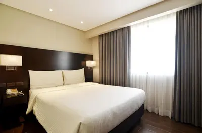 a bedroom with a large bed and a window at Pearl Garden Hotel in Manila
