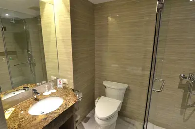a bathroom with a toilet and a sink and a shower at Pearl Garden Hotel in Manila