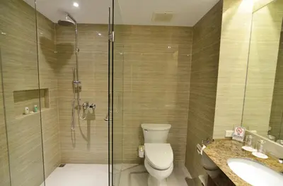 a bathroom with a shower and a toilet and a sink at Pearl Garden Hotel in Manila