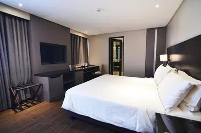 a hotel room with a white bed and a desk at Pearl Garden Hotel in Manila