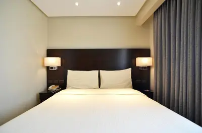 a bedroom with a large white bed with two lamps at Pearl Garden Hotel in Manila